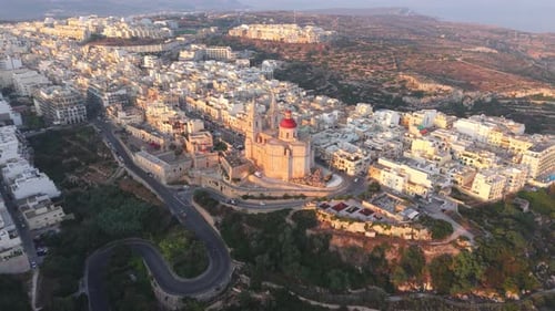 Aerial video of Malta, showcasing the prominent Mellieha Parish Church with its red dome surrounded
