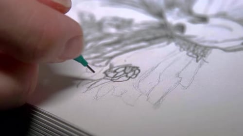 Person sketching with a green pencil on a white paper. Close up shot