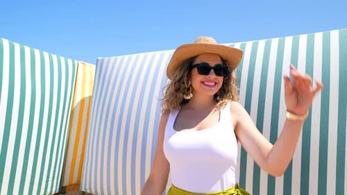 Tourist woman posing on beach with colorful windbreaks