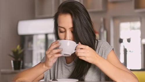 Woman drinking coffee in a bright, modern kitchen
