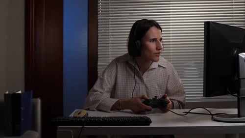 Woman Plays Video Game with Controller at Desk