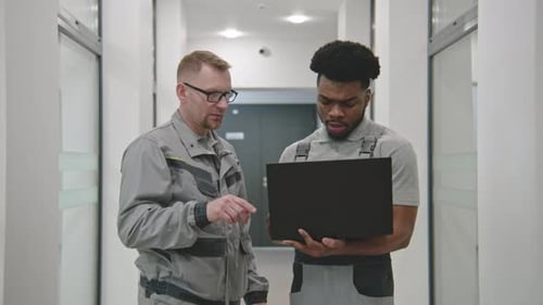 Men Wearing Uniforms Using a Laptop Indoors