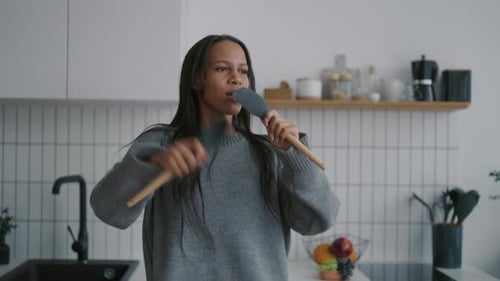 Carefree Woman Singing and Dancing with Kitchen Utensils