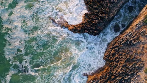 Blick von oben auf raue Wellen, die weißen Schaum bilden, das Meer, das Surfen auf den Küstenklippen