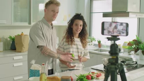 Vídeo de una pareja grabando una receta para un vlog de cocina en la cocina
