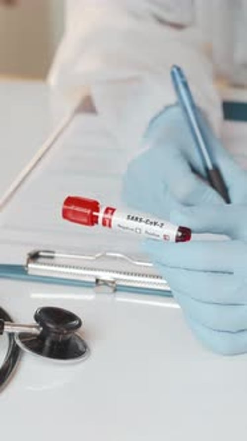Medical Professional Writing Notes on Coronavirus Test