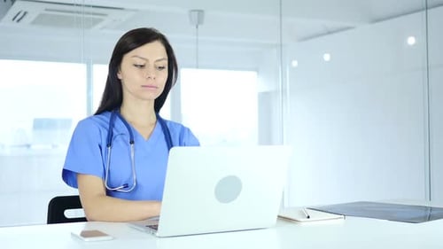 Female Doctor Typing on Laptop in Hospital