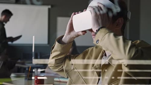 Young IT Specialist Using VR Headset with Remote Controller during Workday