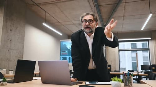 Angry dissatisfied businessman in a formal suit arguing sitting at workplace in business office.