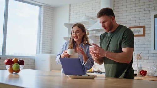 Young Couple Using Laptop in Bright Kitchen