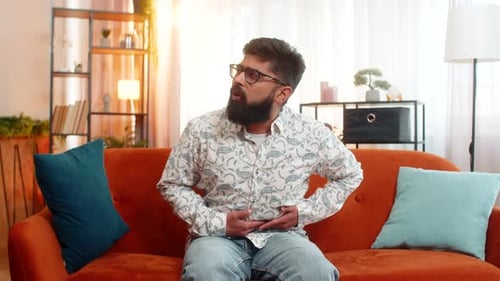 Man with Stomach Pain Sits on Couch