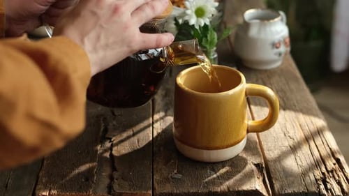 Pouring Tea into a Yellow Mug at Home