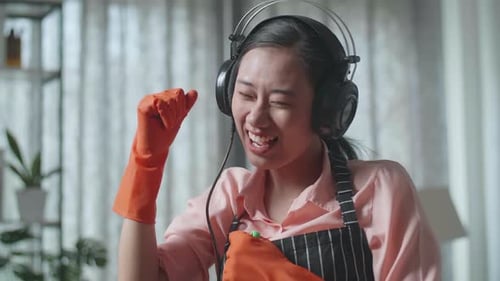 Close Up Of Asian Female Housekeeper Listening To Music, And Dancing While Mopping The Floor At Home