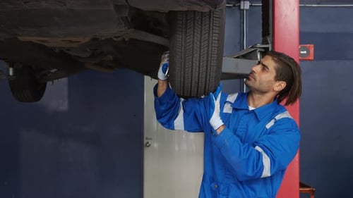 Junger Mann ist Mechaniker Reparatur Reifen Radauto in der Garage mit professionellem Autoservice.