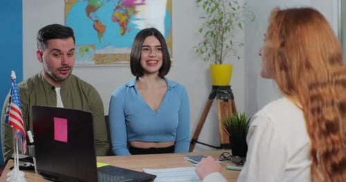 A Young Couple in a Travel Agency Choose a Country for a Summer Trip