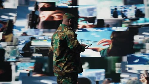 Soldier with Tablet Stands Before Multiple Screens