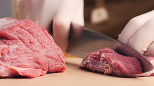 Gloved Hands Slicing Fresh Meat on Cutting Board