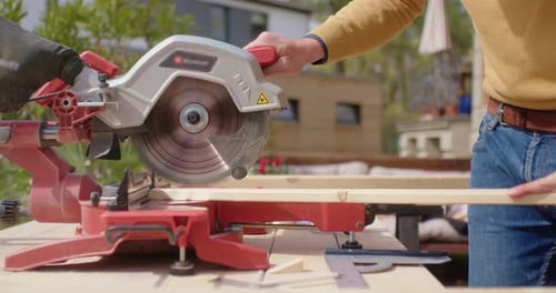 craftsman sawing the wood in the garden