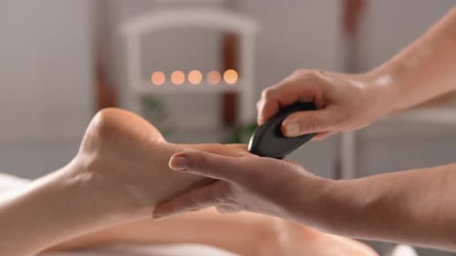 Détente et confort : masser le pied d'une femme avec des pierres chaudes, ce qui renforce la sensation de