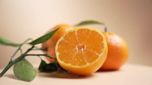 Die
Mandarinenhälfte dreht sich mit einem Zitruszweig und Blättern im Vordergrund.
S
