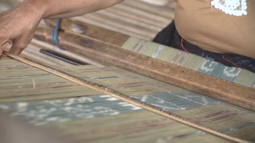 Hand of woman weaving using traditional loom