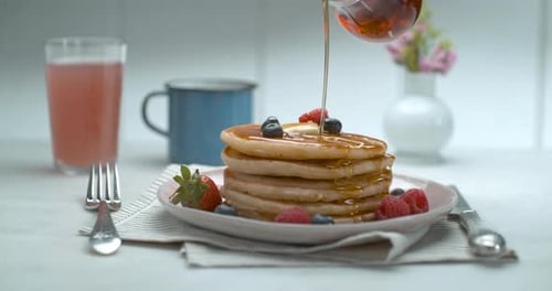 Bottle of Maple Syrup Being Poured Over a Stack of Delicious Plate