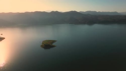 Aerial drone flying over a lake, water dam, with mountains at sunrise. Beautifull dreamy landscape