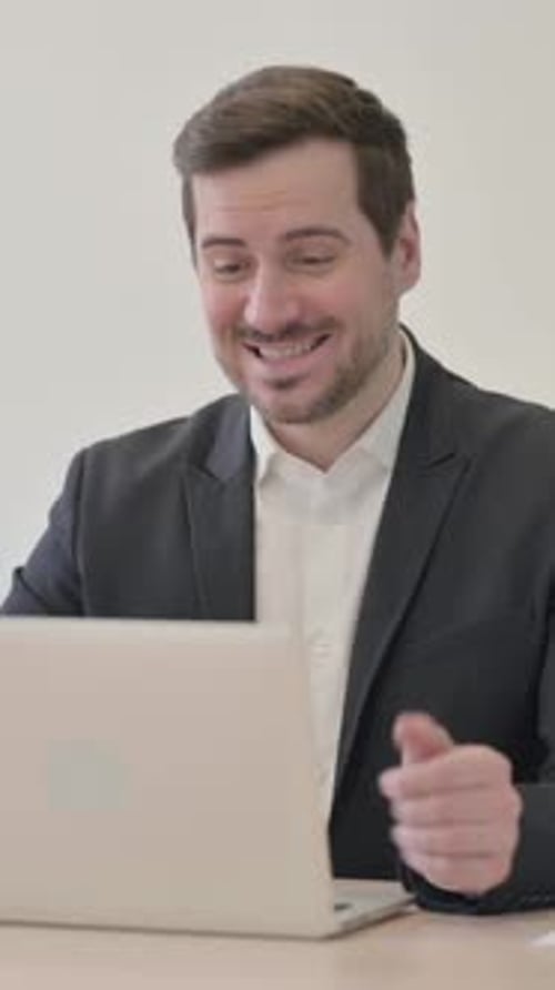 Businessman Video Conferencing on Laptop in Bright Office