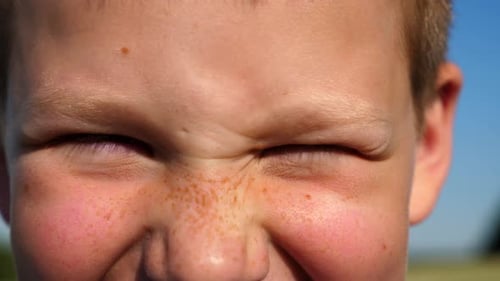 Child Squints Eyes in Close Up Shot