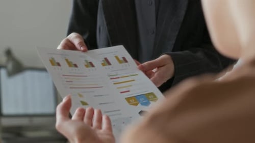 Adults Reviewing Charts in an Office Workplace