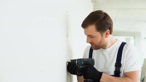 Construction Worker Screws Screw Into Wall
