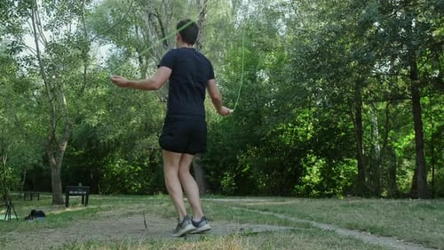 A man in sportswear enjoys jump rope exercises in the park, maintaining his fitness and health with