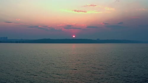 A Beautiful Big Sun Sets Outside the City on a Hill Near the Lake