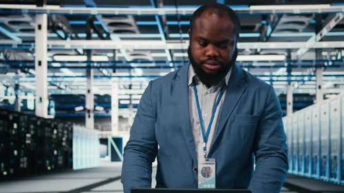 Technician Working on Laptop in Modern Server Room