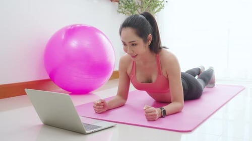 Woman Planking Indoors Watching Laptop for Online Fitness