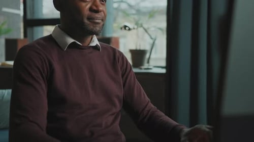 Erschießung eines unrasierten Afroamerikaners, der mit einer digitalen Maus am Schreibtisch vor dem Computer sitzt