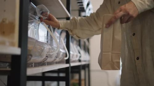 Mujer usa una cuchara de plástico para verter harina en una bolsa de papel