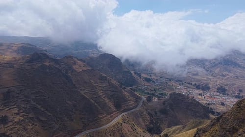 Low Hanging Clouds Drifting Above Andean Peaks Unveiling Lush Valley with Geometric Farmland