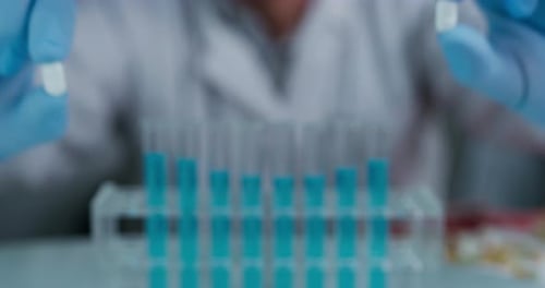 Porträt eines Wissenschaftlers, der in einem Labor ein paar Pillen in der Hand hält und zeigt. Konzept: Chemie,