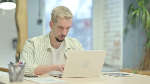 Man Working on Laptop in Bright Office