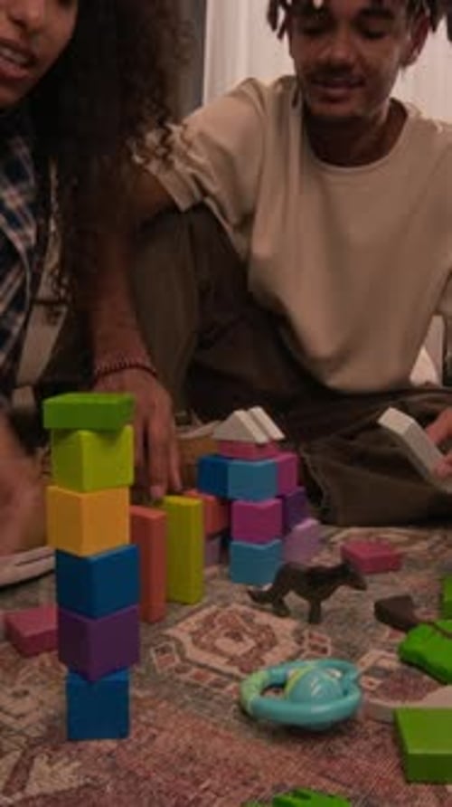 Punto de vista vertical de una pareja joven con un niño jugando a los juguetes en la sala de estar