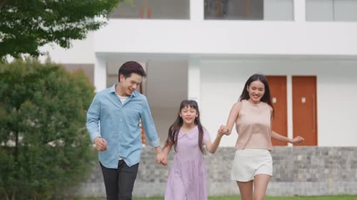 Asiatisch liebende Eltern gehen mit ihrer kleinen Tochter draußen im Garten spazieren.