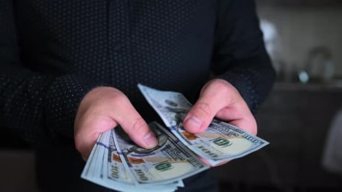Men's hands count money and give part to another person, close up.