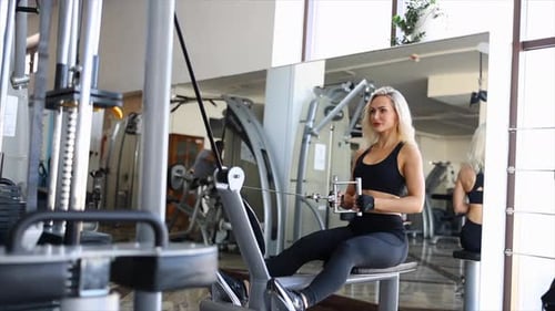 Determined sportswoman performing seated cable rows in modern gym
