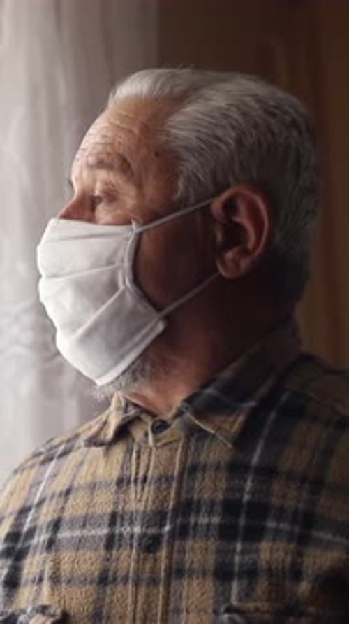 An Elderly Man Gazes Out the Window Reflecting on Life During the Ongoing Pandemic Crisis