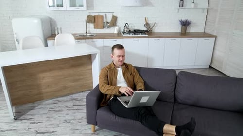 Homme séduisant travaillant et assis dans une maison moderne. Heureux homme embarrassé travaillant en quarantaine.