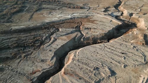 Aerial view of the cracked landscape on a sunny day, drone flying forward - Scenic view of the lands