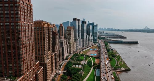 Flying along the green area at Hudson waterfront. Busy highway full of cars at daytime. Top view.