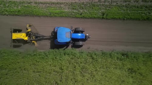 Grader works with tractor and levelling the field road
