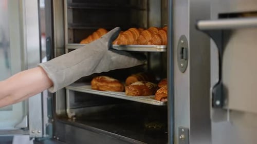 Fresh Baked Croissants Pulled from Oven by Baker